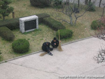 photo of two boys resting in the school courtyard with their brooms