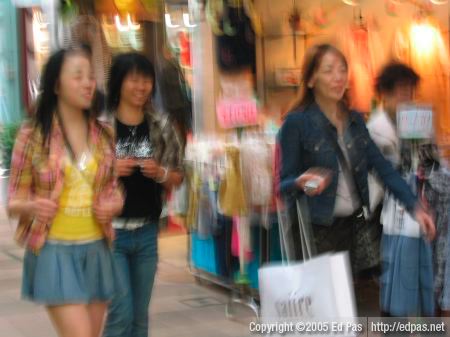 a blurry photo of three girls walking through the Kokura arcades
