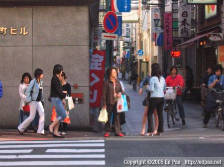 shoppers making their way past people waiting to cross a street in Kokura