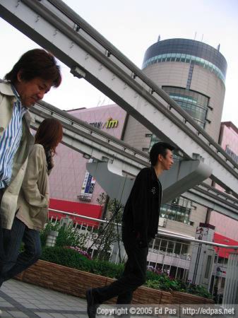 black-clad man with Isetan and monorail tracks in the background